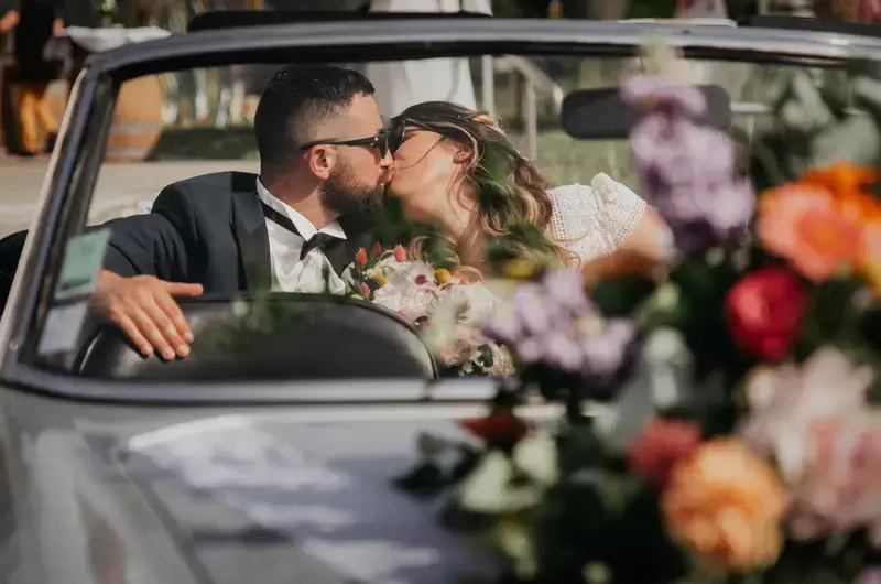 Le couple s'embrasse dans une voiture ancienne décorée de fleurs colorées

